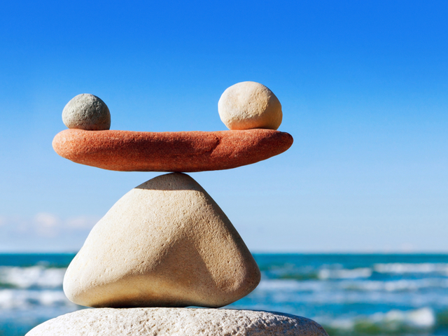 Rocks balancing atop one another, with the ocean in the background - technology vs upskilling concept
