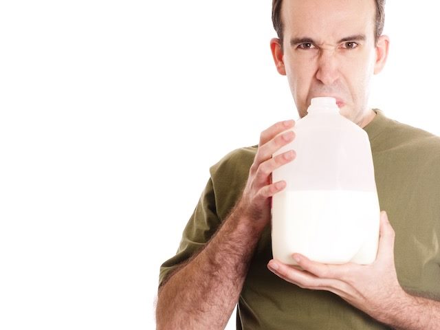 cornball photo of man smelling sour milk and overreacting