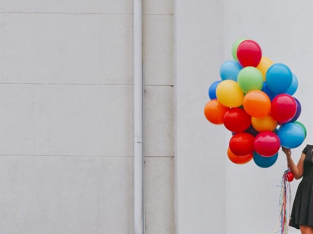 woman holding a number of colorful balloons