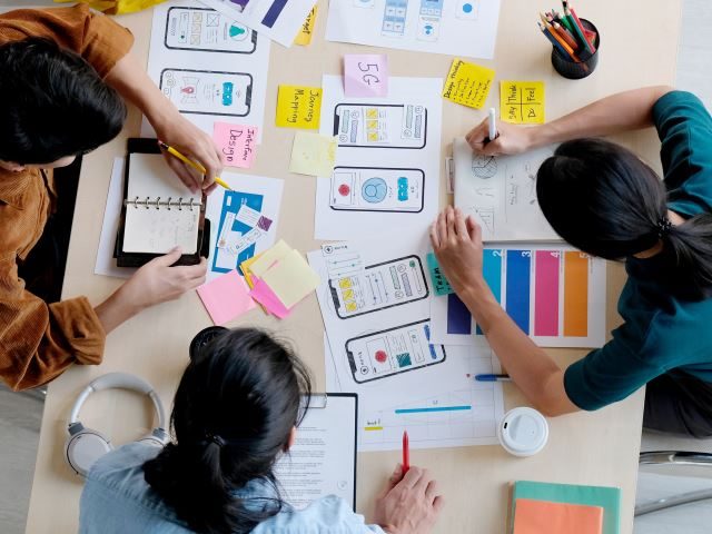 A group of marketers working on a customer journey and smartphone UI elements