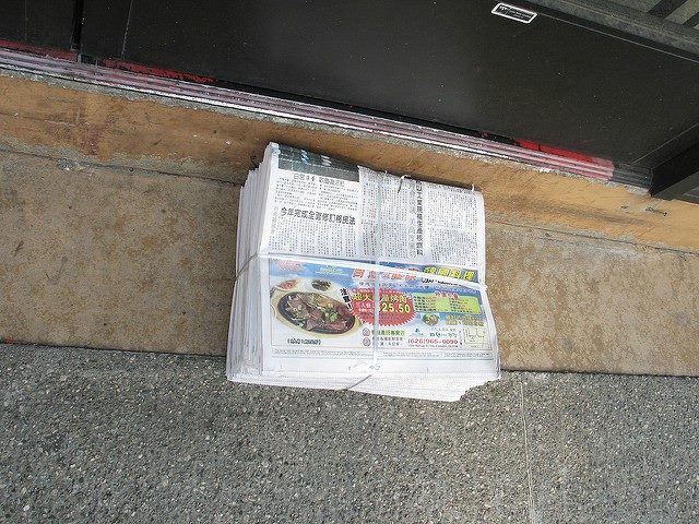 Stack of newspapers bundled on the ground.