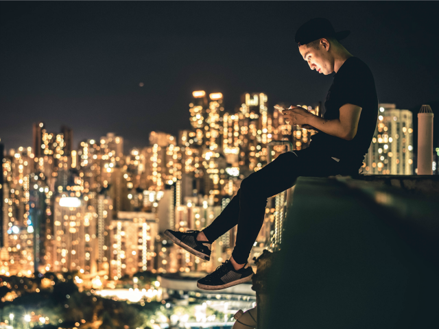 man using a mobile device with city view in background