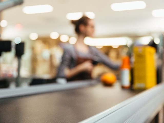  Young female cashier scanning grocery items, blurred. 