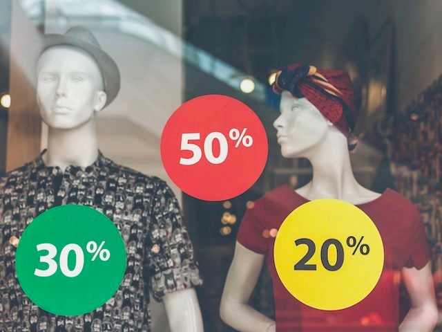 store window display with mannequins, multiple discount tags on window
