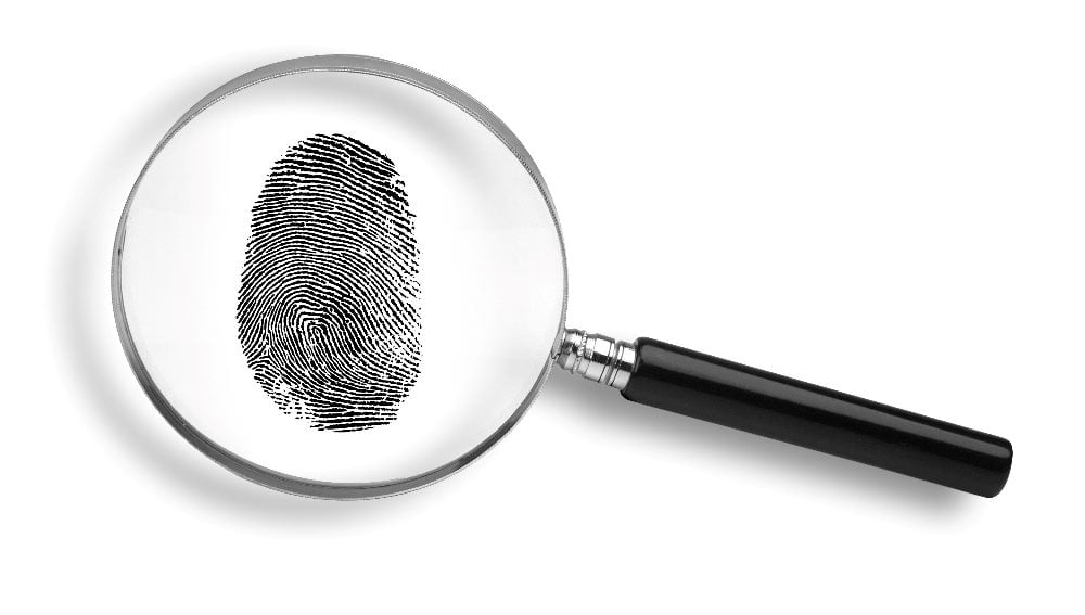 A magnifying glass lies on top of a black fingerprint on a white background in piece about the unintended consequences of using AI in marketing.