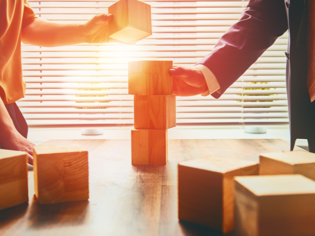 A businesswoman and businessman stacking wood blocks in an office. - building a business plan concept