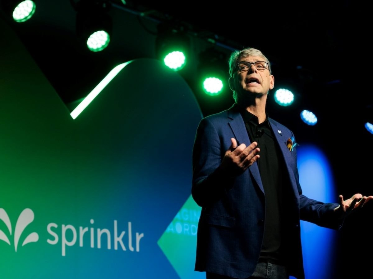 Sprinkr CEO Rory Read giving an address on stage with a Sprinklr logo behind him.