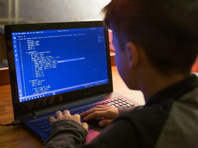 Young boy coding on laptop at night.