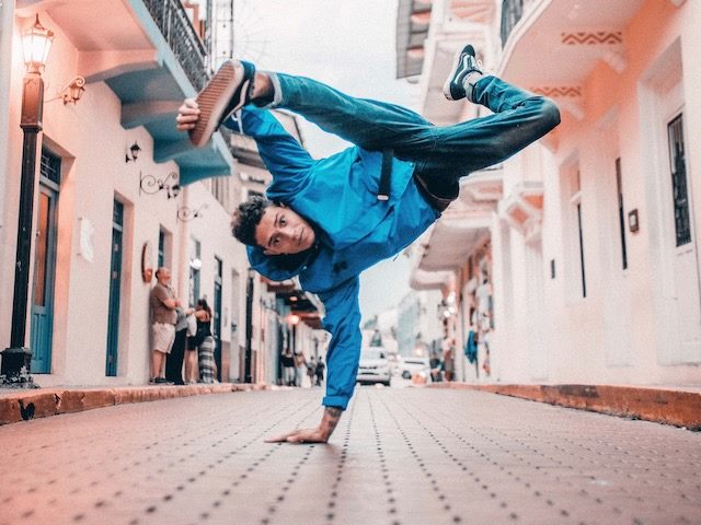 man balancing on one hand in middle of breakdancing move