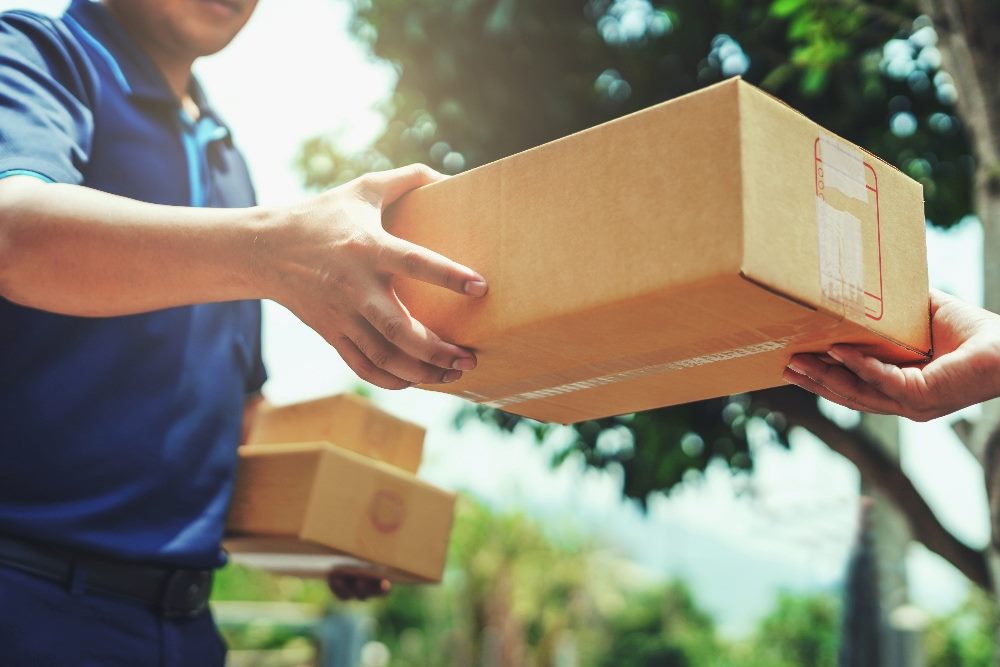 A delivery person hands a parcel to a recipient in piece about AI customer experience solutions.