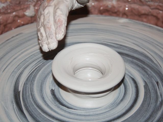 person working clay on a pottery wheel