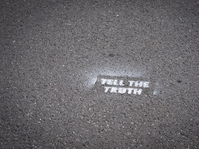 graffiti on sidewalk that reads: "Tell the truth"