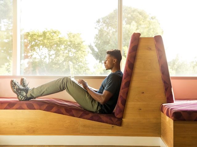 man working on a laptop sitting in what looks like a really uncomfortable chair