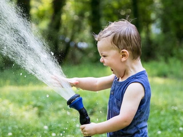 toddler playing with water hose