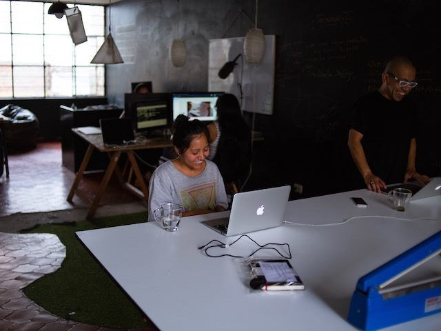 woman laughing while sitting at desk in front of her laptop