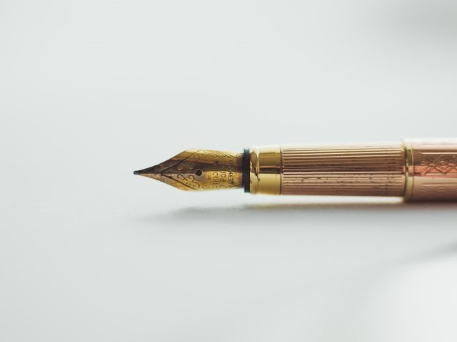 An old-fashioned ink pen on a white background - SaaS SLA contract considerations concept