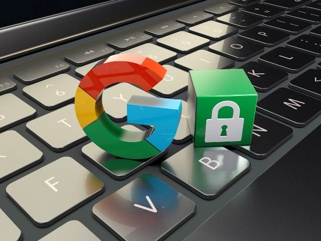 A multi-colored, red, blue, yellow and green, "G" for Google sits atop a laptop on the keyboard next to a  green tile with a padlock symbol, representing the threat of Google privacy issues.