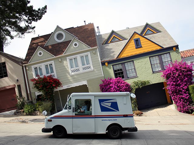 Image of a postal truck in front of what looks like slanted houses. 