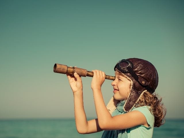 Happy kid looking into a telescope-like device. 