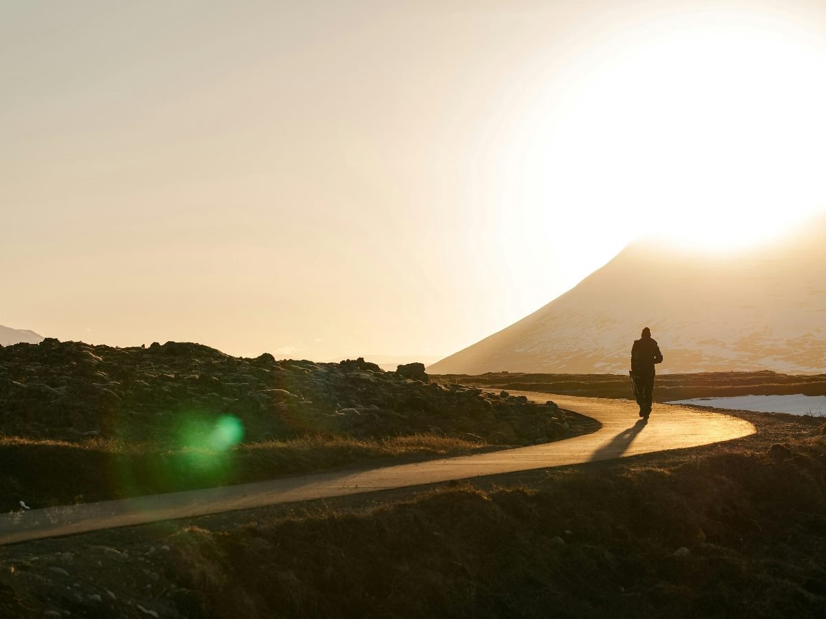 Person walking in the distance on windy road at sunset.