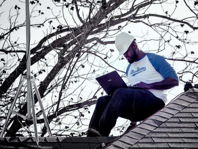 worker on roof using a computer