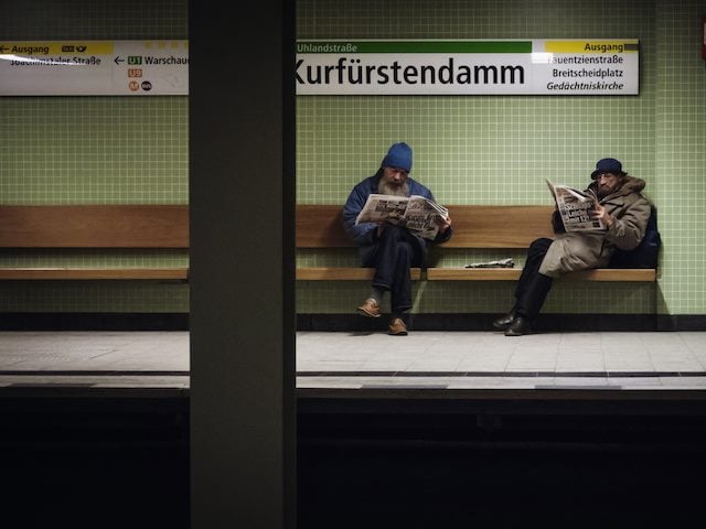 two men reading newspapers in the Berlin UBahn