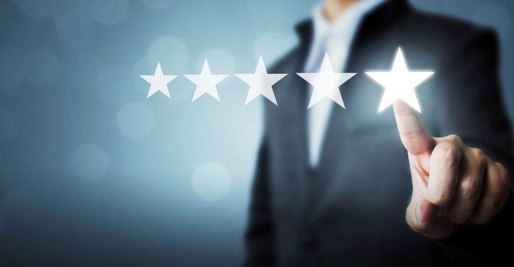 A man wearing suit is pointing at five star symbol indicating the importance of companies focusing on customer success and retention.