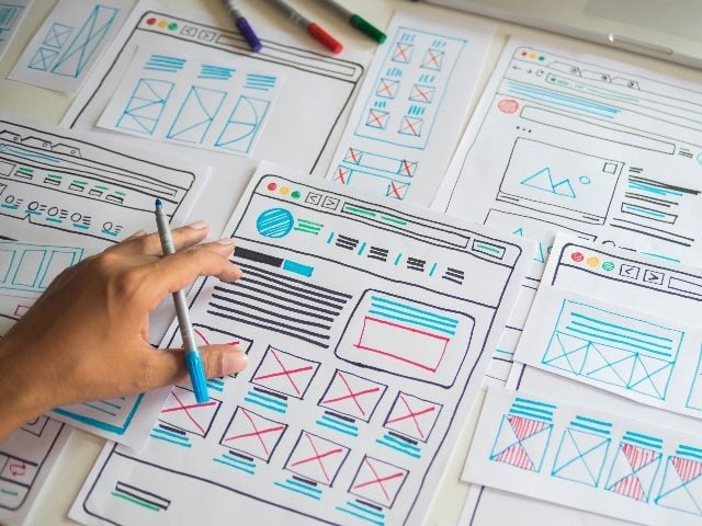 Person (showing just hands) sketching template layout prototype framework wireframe for user experience. 