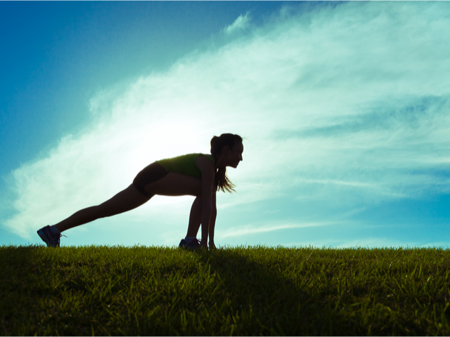 A female runner silhouetted in the start position