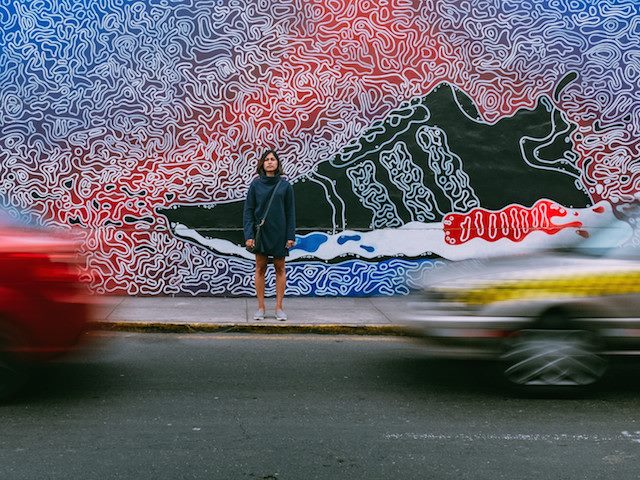 a mural of a sneaker advertisement with a woman standing in front