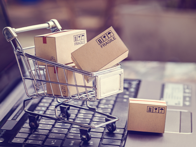Shipping boxes loaded into a shopping cart on top of a laptop keyboard - ecommerce concept