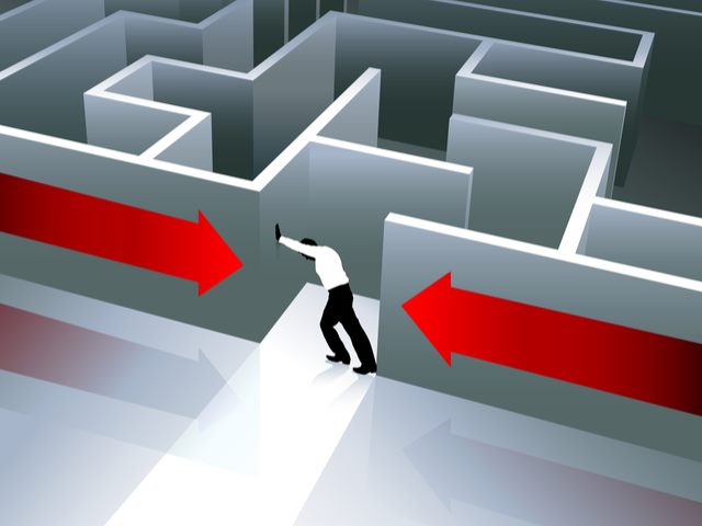 An office worker pushing away the walls of a maze.