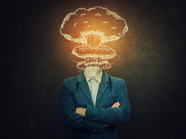 A man with crossed hands, his head exploding like a nuclear mushroom cloud over a blackboard background - headless cms concept