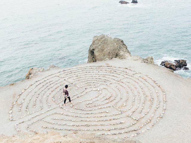 woman walking in a maze next to water