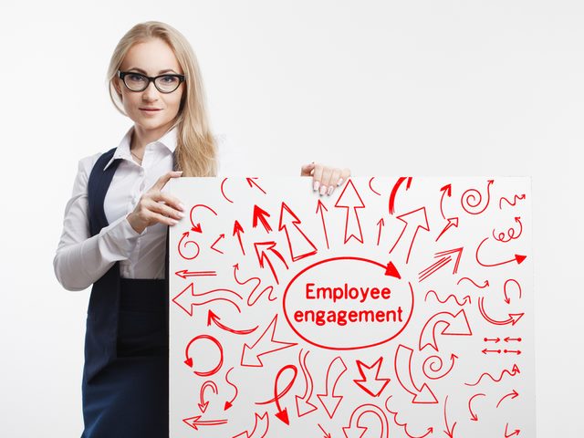 Woman holding up a sign that says employee engagement with many arrows pointing in many directions