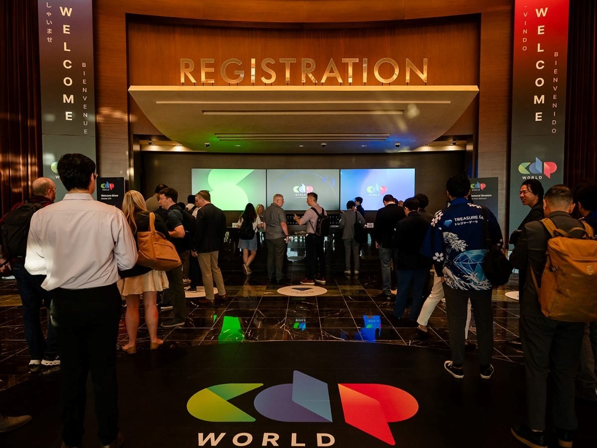Attendees gather in the registration area at Treasure Data’s CDP World conference, standing in line beneath a large “Registration” sign with multilingual “Welcome” banners and the colorful CDP World logo displayed on screens and the floor.