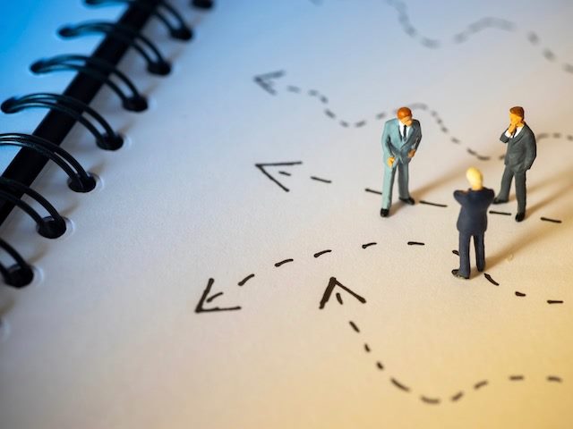 figurines of business men-types discussing a decision on a notebook