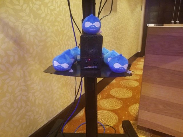 Stuffed Drupal-logo heads on a TV-stand post at Acquia Engage.