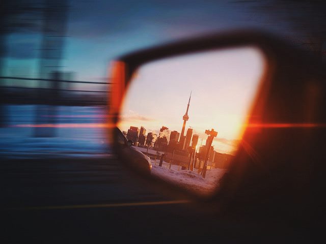 view of Toronto visible in rearview mirror of speeding car