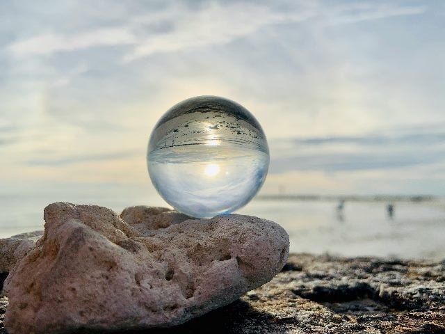a crystal ball on a rock near the ocean.