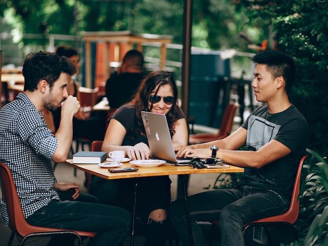 group of people drinking coffee, talking, looking at a laptop