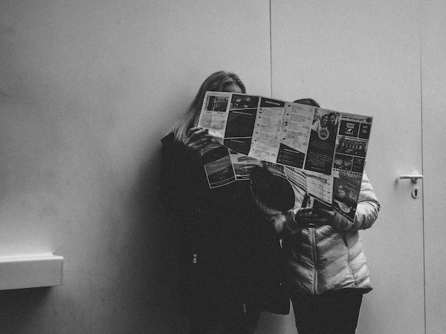two people sharing a newspaper