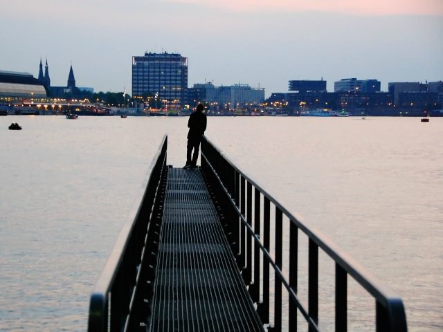 person looking to the horizon from the edge of a dock