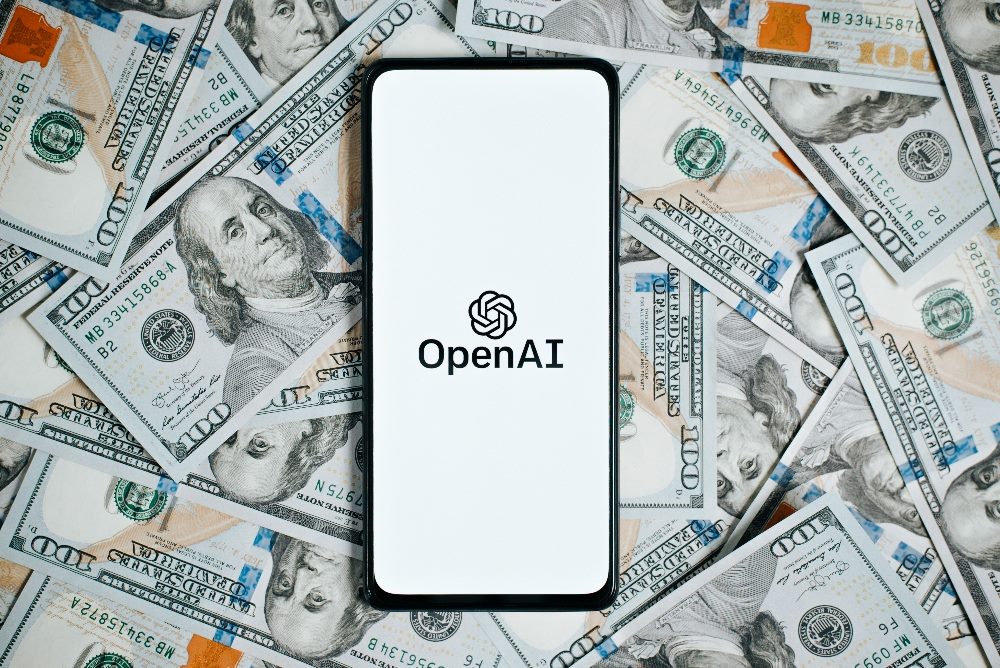 OpenAi company logo on screen of smartphone lying on money background of one hundred dollar bills in piece about GPT store launch.