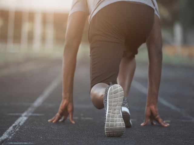 A man, a runner, taking off out of the starting blocks.. The man is running away from the shot