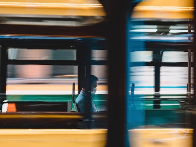 person on an empty bus wearing a mask