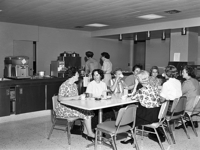 Black-and-white photo of women sitting at a lunch table during a break from work in the 1960s.