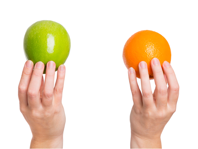 hands holding and comparing an apple and an orange on white background -  Agile, SCRUM or Kanban concept