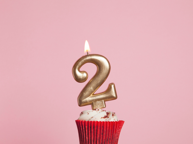 A birthday cupcake with a number 2-shaped lit candle.