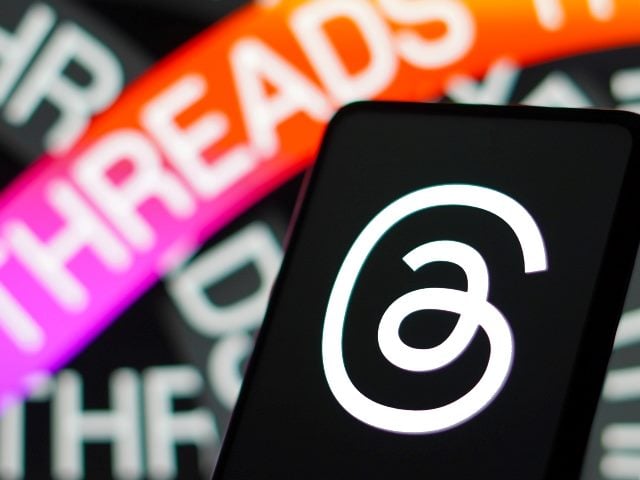 Threads black and white  logo on a smartphone screen with overlapping ribbons with the word "Threads" on them. One is bright pink.